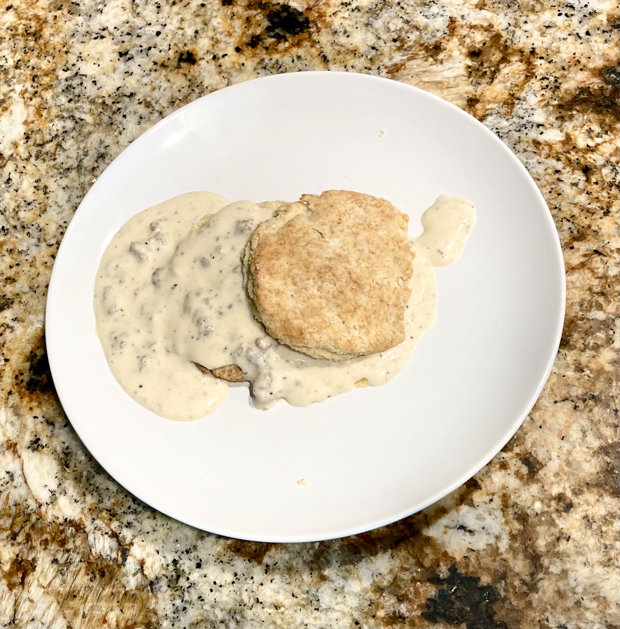 A biscuit smothered in sausage gravy on a plate